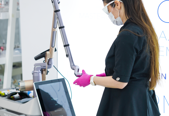 Cursantă a Colegiului de Estetică setând parametrii unui aparat laser profesional